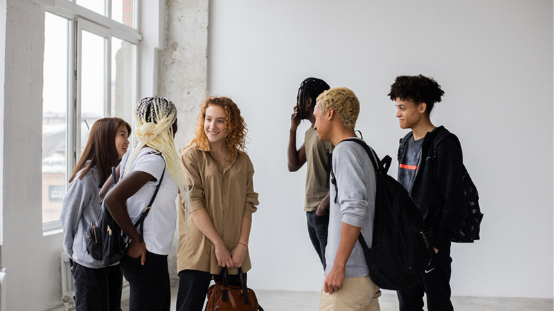 A group of teenage students conversing in a school setting.